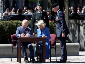 Die Herzogin von Cornwall und der Prinz von Wales signieren am 18. Mai 2022 ein Buch im National War Memorial in Ottawa.