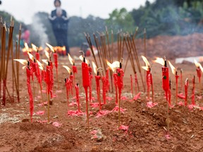 Near the site of the accident, people burn candles and incense sticks during a Buddhist ceremony in honour of the crash victims.