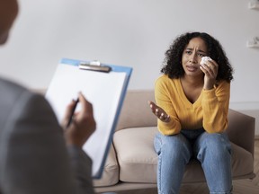 Young African American woman crying on session with psychologist, speaking to mental health professional at office