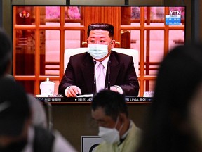 People sit near a screen showing a news broadcast at a train station in Seoul on May 12, 2022, of North Koreas leader Kim Jong Un appearing in a face mask on television for the first time to order nationwide lockdowns after the North confirmed its first-ever COVID-19 cases.