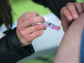 File: Health worker administers COVID-19 vaccine.