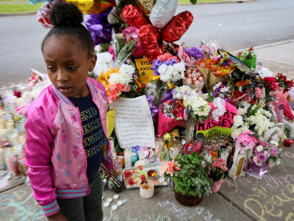A  young girl visits the makeshift memorial to victims of the May 15 mass shooting at a Tops supermarket in Buffalo, New York.