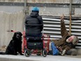 A homeless man talks to a woman and her dog in downtown Ottawa. We pat ourselves on the back for donations to shelters, blithely unaware about how minimally any have improved homelessness in our city.