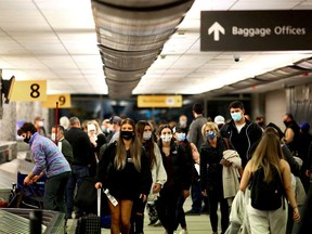 FILE PHOTO: Travellers wearing protective face masks to prevent the spread of the coronavirus disease (COVID-19) reclaim their luggage.