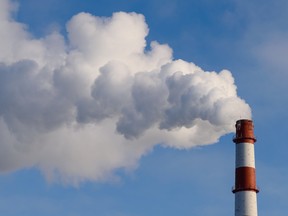 The pipe smokes against the blue sky. - stock photo getty images carbon tax emissions pollution