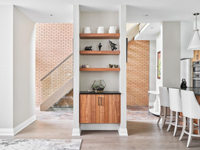 This ground-floor space is a hybrid of open-concept and defined rooms, says Hill. The shelving wall divides the living room from the entry area so that they feel like separate rooms, but leaves views through to the sunlight falling on the brick and stairs behind. “The built-ins add character and functionality to the living room, but also are part of this visual layering of spaces.”