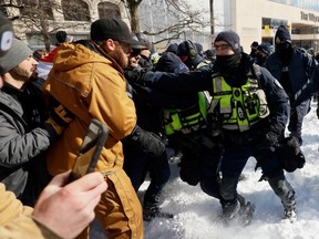 Police push back during a sweep against the Freedom Convoy protest in Ottawa, February 18, 2022.