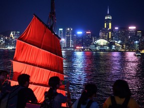 Tourist take pictures in front of a traditional Chinese junk boat as the Hong Kong skyline is seen across Victoria Harbour. "While Hong Kong was occupied by the British following the Opium War, it remained Chinese territory," one new textbook in China says.