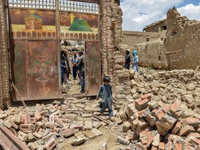 TOPSHOT - A child walks out from inside a gate of a house damaged by an earthquake in Bernal district, Paktika province, on June 23, 2022.
