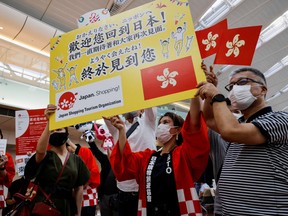 Members from Japan's shopping and tourism companies hold a placard reading 'Welcome back to Japan! We finally met you!' as they greet a group of tourists from Hong Kong upon their arrival at Haneda airport, as Japan gradually opens to tourists after two years of coronavirus disease (COVID-19) restrictions, in Tokyo, Japan.
