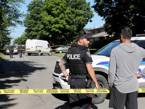 Ein Mann spricht mit der Polizei, bevor er in das Haus neben dem Haus in der Anoka Street gelassen wird, in dem die Polizei von Ottawa und die SIU am Dienstag drei Todesfälle untersuchten.  Julie Oliver/Postmedien