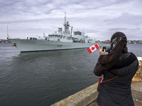 A woman takes a photo as HMCS Halifax departs Halifax on March 19.