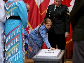 Leia Quesnel, 8, with her mom and Canadian Armed Forces member Caitlin Quesnel, reaches out to touch the newly-unveiled symbols. Her late father, Cpl. Justin Quesnel, was the first Canadian soldier to have his spirit name and the Medicine Wheel symbol on his headstone.