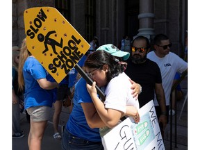 Jazmin Cazares, 17, right, the sister of Jackie Cazares, who was killed in the Robb Elementary School shooting in Uvalde Texas, gets a hug during a "March for Our Lives" rally on June 11. The 21 holes in Cazares's sign represent the 21 victims of the shooting in Uvalde.