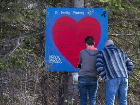 People pay their respects at a roadside memorial in Portapique, N.S. on Sunday, April 26, 2020.The RCMP struggled to inform families promptly about the loss of their loved ones in the aftermath of the 2020 Nova Scotia mass shooting, with a single officer handling most cases amid an "astronomical" flow of information.&ampnbsp;THE CANADIAN PRESS/Andrew Vaughan