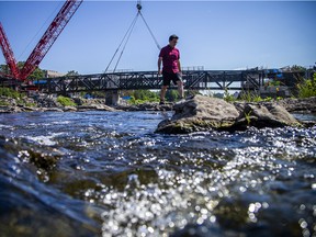 A spectator has the right idea to stay cool watching the new pedestrian and cycling bridge spanning the Rideau River being eased into place Saturday, July 23, 2022.
