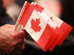 A boy holds a Canadian flag during a citizenship ceremony