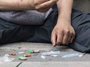 OTTAWA - A man takes drugs on Rideau St. in May. A batch of tainted drugs that arrived in Ottawa earlier this month is being blamed for scores of overdoses throughout the city that overwhelmed outreach workers and first responders and led to at least five deaths.