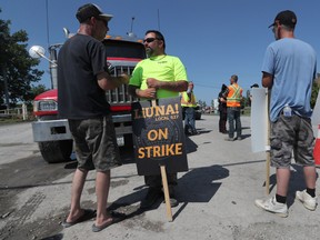 Construction workers from LiUNA Local 527 walk the picket line at Moodie Drive in Ottawa on Tuesday before the announcement that a tentative agreement had been reached.
