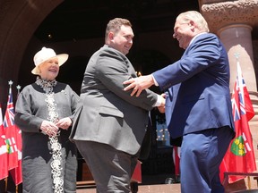 Minister of Citizenship and Multiculturalism, Michael Ford shakes hands with Premier Doug Ford as Lieutenant-Governor of Ontario Elizabeth Dowdeswell looks on, at the swearing-in ceremony at Queen's Park in Toronto on June 24, 2022.