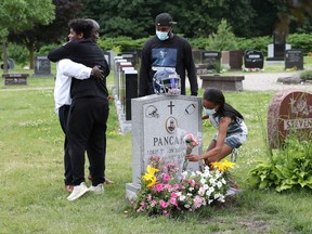 Jooris Ndongozi, the father of Tyson Ndongozi, who was shot to death a year ago, greets Tyson's friends at his son's grave Tuesday.