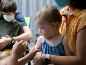 Two-year-old Beatrice Giles warily watches the needle as she sits on the lap of her mom, Kristina Pawk, while getting her COVID-19 vaccine on Thursday.