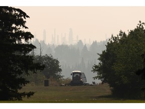 A City of Edmonton worker goes about ther day as smoky skies are seen from Kinnaird Park on Monday, Aug. 22, 2022. Environment and Climate Change Canada issued a Special Air Quality Statement due to smoke from wildfires. The impacts of climate change are increasing.