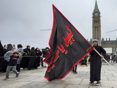 Eight-year-old Mohammad Alabedy carries a flag on Parliament Hill during a commemoration of the martyrdom of Imam Hussain, grandson of the Islamic prophet Mohammad, on Monday, Aug. 8, 2022.
