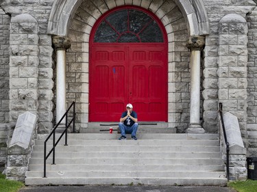 A supporter of The United People of Canada (TUPOC) prays on the steps of a former St. Brigid's church in Lowertown. Sunday, Aug. 21, 2022.