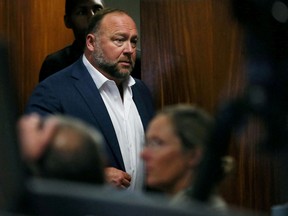 FILE PHOTO: Alex Jones walks into the courtroom in front of Scarlett Lewis and Neil Heslin, the parents of 6-year-old Sand Hook shooting victim Jesse Lewis, at the Travis County Courthouse in Austin, Texas, U.S. July 28, 2022.