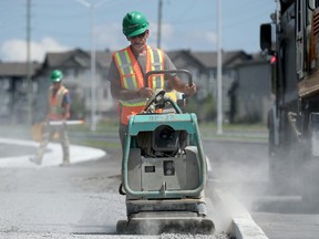 A worker packs granular for a new sidewalk along Strandherd Drive  during the scorching summer heat of August.