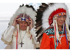 Pope Francis adjusts his headdress after it was given to him by Chief Wilton Littlechild (at right), during his visit to Canada last week.