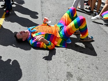 Ontario NDP Member of Provincial Parliament for Ottawa Centre Joel Harden lays on the ground after a powerful high five from a young child during the 2022 Capital Pride Parade in Ottawa on Sunday, Aug. 28, 2022.