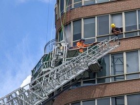 Ottawa Fire on scene on Grant Carmen Dr. for two workers stuck on a swing stage 10 stories above the ground. OFS Rope Rescue technicians rigged a safety line before transferring them to Ladder 24.