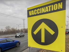Cars drive past a sign for a vaccination centre.