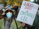 Ria Heynen von den Raging Grannies hält während einer kürzlichen Demonstration vor dem Rathaus von Ottawa ein Schild über die Auswirkungen von COVID auf Langzeitpflegepatienten hoch.  Jetzt will die Regierung von Ontario die Älteren noch einmal schikanieren. 
