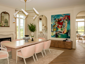 The dining room is oversized for big family gatherings, with archways, a neoclassical fireplace mantel, plush pink chairs and juxtaposed with a five-foot modern light fixture.