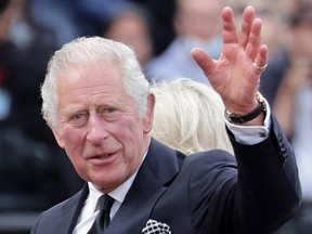 King Charles III waves to the public after viewing floral tributes to the late Queen Elizabeth II outside Buckingham Palace on September 09, 2022.