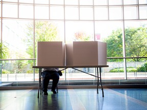 Ein unbekannter Wähler sitzt am Samstag hinter einem Wahlschirm im Rathaus von Ottawa.