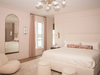 The primary bedroom, with walls in a blush pink, was reconfigured to allow for a walk-through closet behind the bed.
