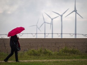 A woman walks with an umbrella along a path near wind turbines at the energy-sufficient village of Feldheim, 80km south of Berlin.