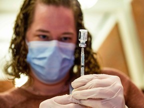 In this file photo, a medical worker prepares the Pfizer-BioNTech COVID-19 vaccine booster. Canadians are facing mixed messages about vaccines depending on where they live in the country.