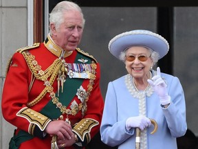 In this photo taken on June 2, 2022, Queen Elizabeth and then-Prince Charles watch a special flypast from the Buckingham Palace balcony as part of platinum jubilee celebrations.