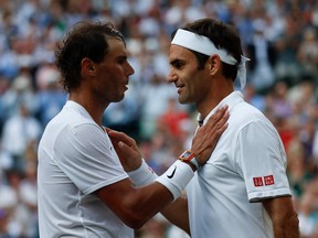 (FILES) In this file photo taken on July 12, 2019 Switzerland's Roger Federer (R) speaks with Spain's Rafael Nadal (L) after Federer won their men's singles semi-final match on day 11 of the 2019 Wimbledon Championships.