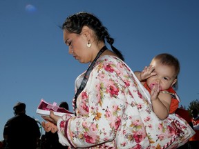 Singer Beatrice Deer, who performed at Friday’s event, and her 16-month-old daughter Inumannaaq share a quiet moment before placing a tiny pair of shoes at the front of the stage at LeBreton Flats.