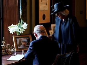 King Charles III and the Queen Consort sign the visitors book at Hillsborough Castle, Tuesday Sept. 13.