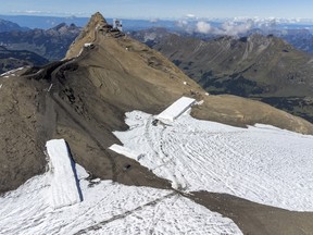 Hikers walk past the newly uncovered Zanfeluron path, as a split of the Sex-Rouge and the Zanfleuron Glacier revealed the path for the first time in 2000 years due to this summer heatwave, at Glacier 3000 in Les Diablerets, Switzerland, September 11, 2022.