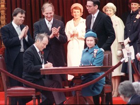 Queen Elizabeth II signs Canada’s constitutional proclamation as Prime Minister Pierre Trudeau looks on during a ceremony at Parliament Hill in Ottawa on April 17, 1982.