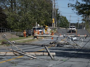 Workers assess downed power poles caused by post-tropical storm Fiona in Dartmouth, N.S. on Sunday, September 25, 2022. Canadians will see lower incomes and a choice between higher taxes or fewer government services if there isn't more effort to adapt to the changing climate, a new report from The Canadian Climate Institute warns.