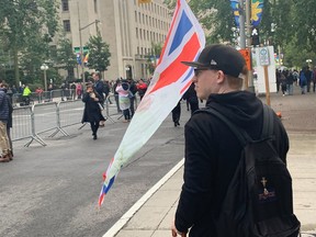 OTTAWA – Sept. 19, 2022 – Troy Dexter waves a Union Jack bearing the Queen?s likeness as he walks alongside the parade to honour the life of Queen Elizabeth II.